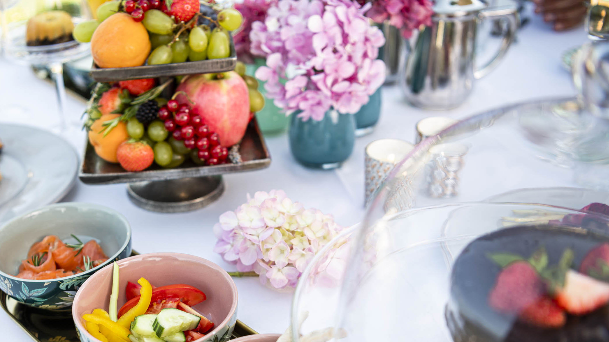 Frühstück de luxe im Garten mit schön gedecktem Tisch mit Früchten, Lachs, Gemüse, Schokoladekuchen