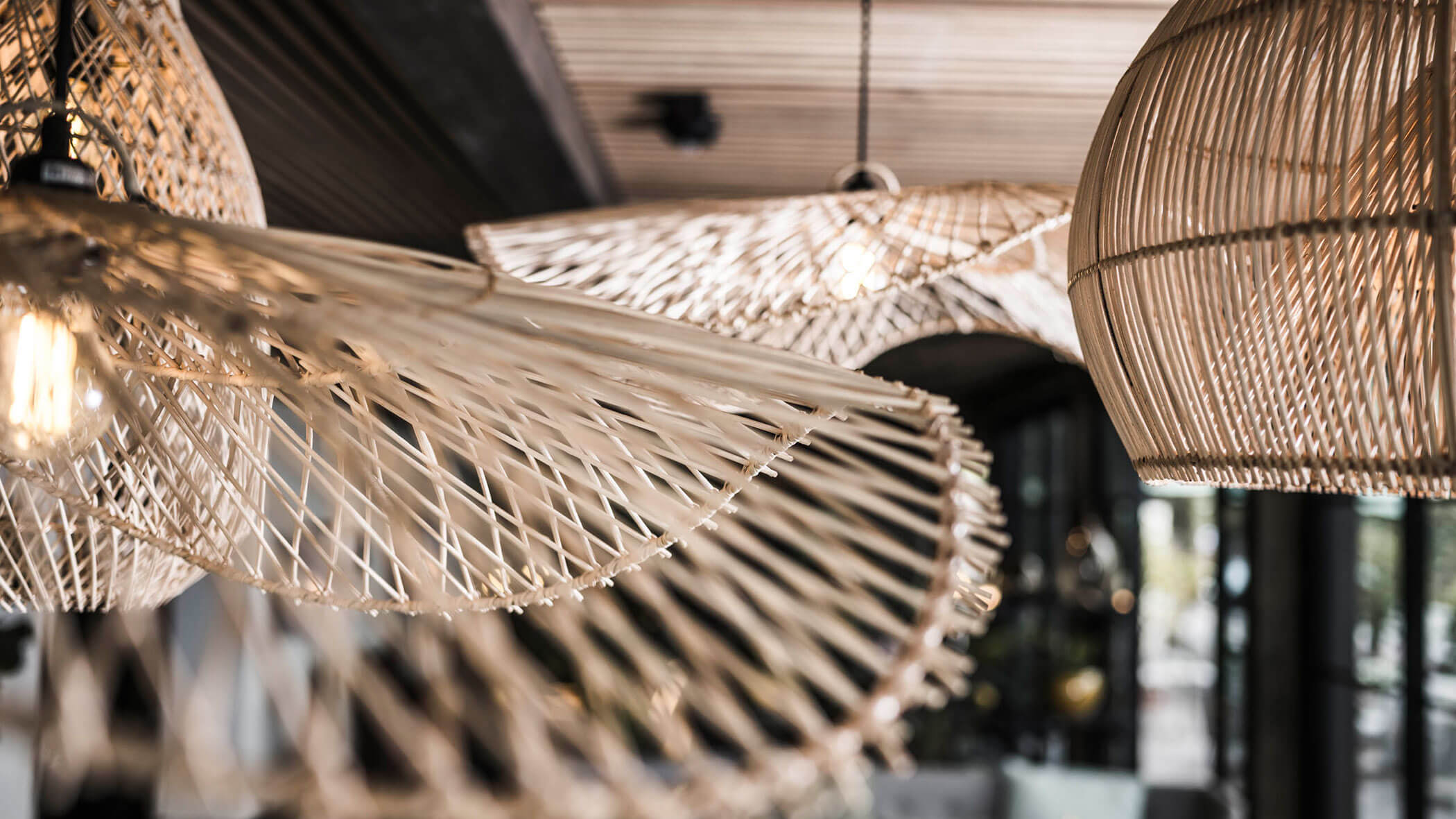 Close-up of modern woven rattan pendant lights hanging in a stylish, contemporary indoor space. - Hotel Lagrein