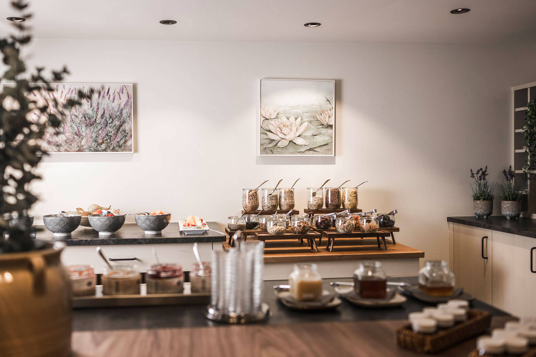 Breakfast buffet with cereals, jars, fruit bowls, and neatly arranged condiments in a modern, bright room. - Hotel Lagrein