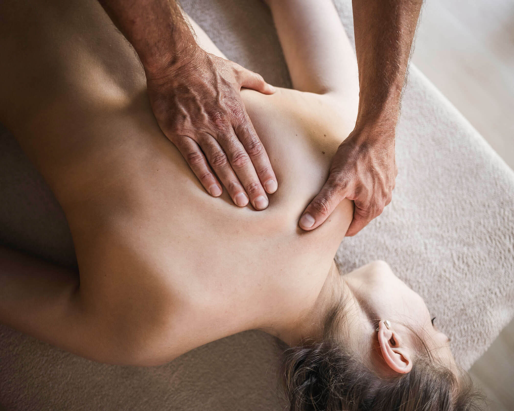 Person receiving a back massage while lying face down on a massage table. - Hotel Lagrein