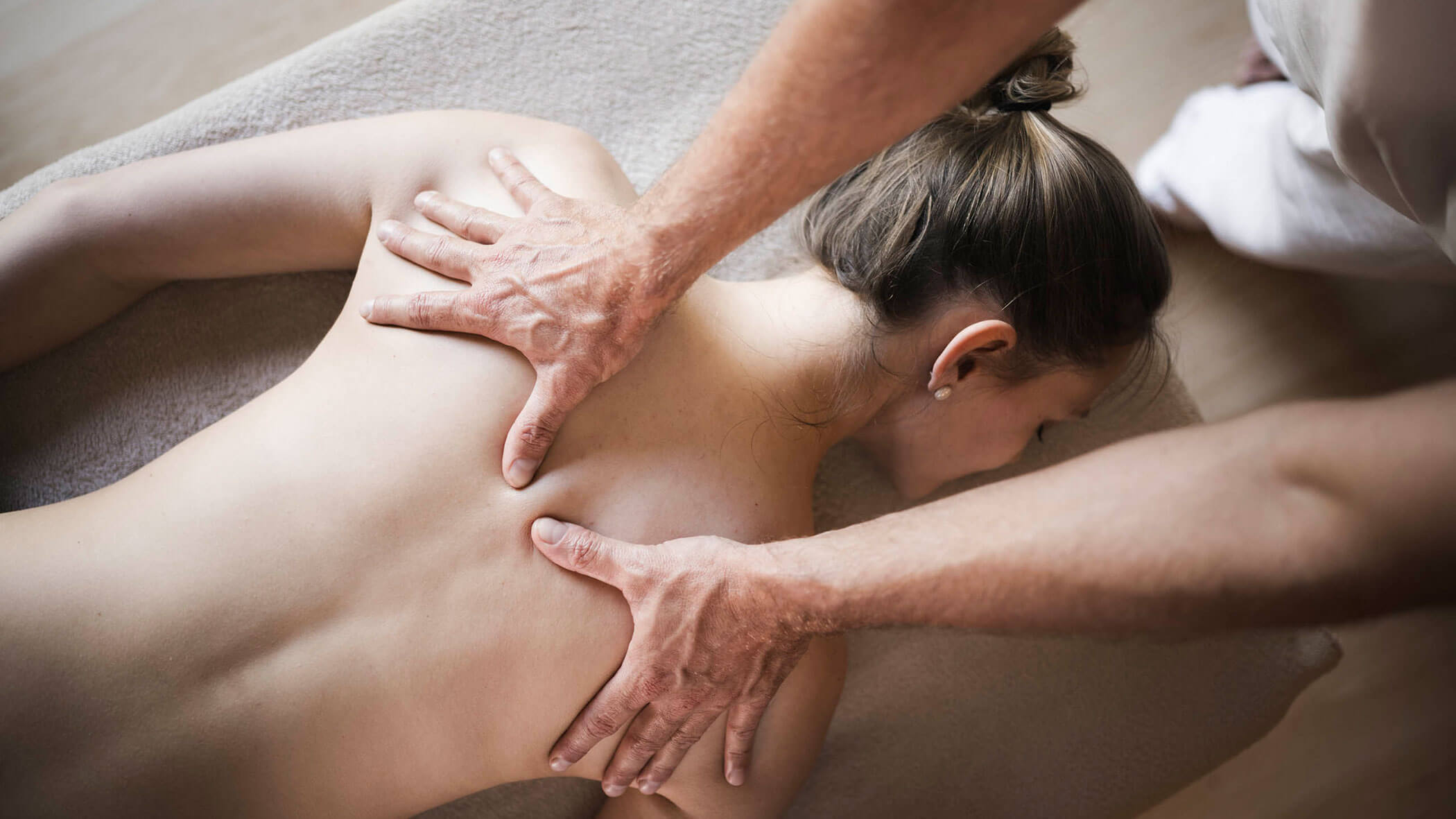 A person receives a back massage while lying face down on a massage table. - Hotel Lagrein